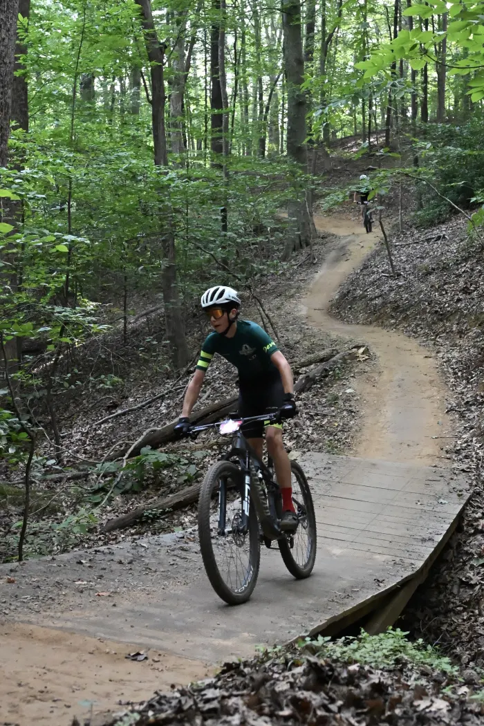 A Pine Tree Devo rider on a wooden trail bridge in the woods